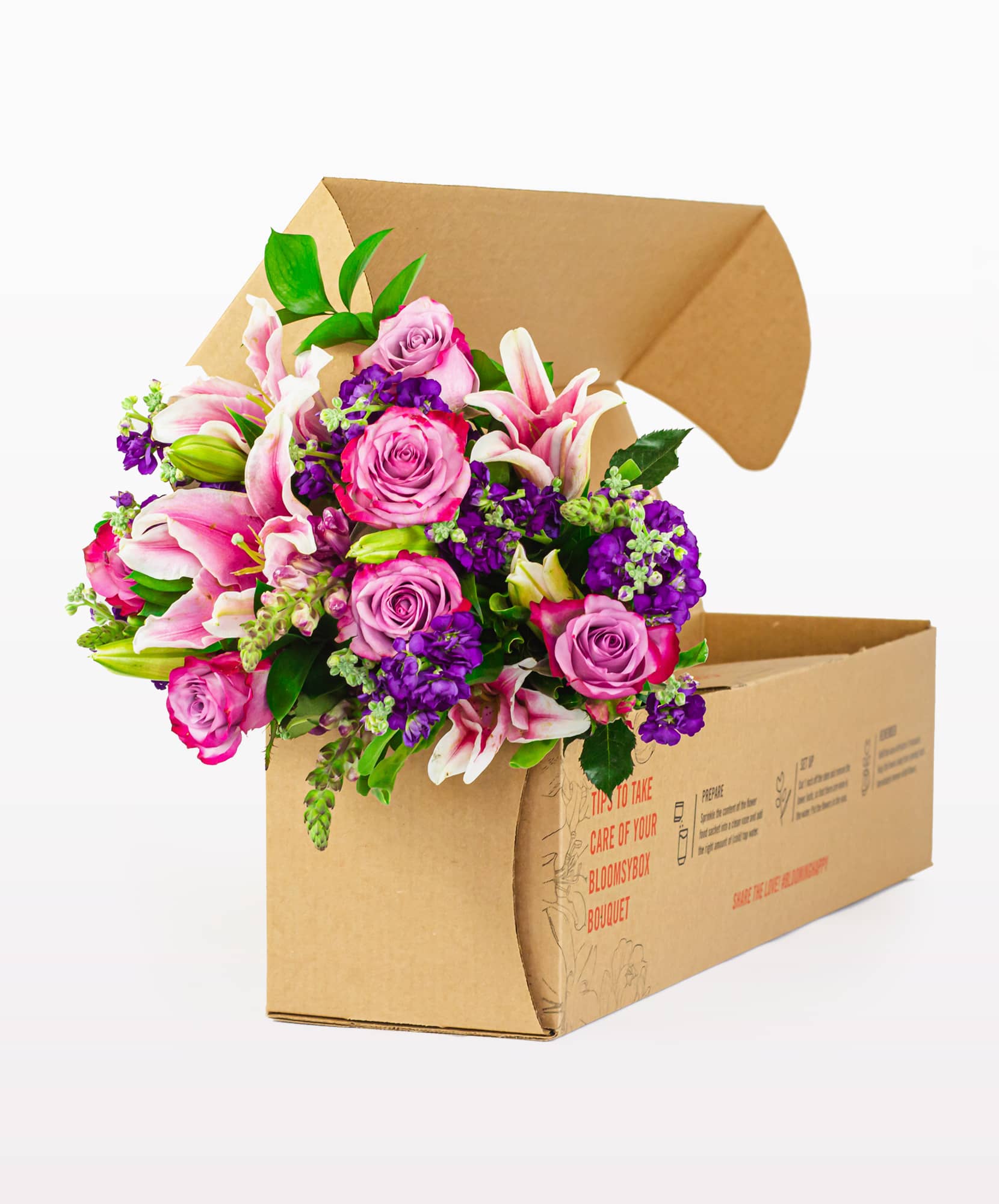 A vibrant bouquet featuring pink lilies, purple asters, and roses, elegantly packaged in a box.