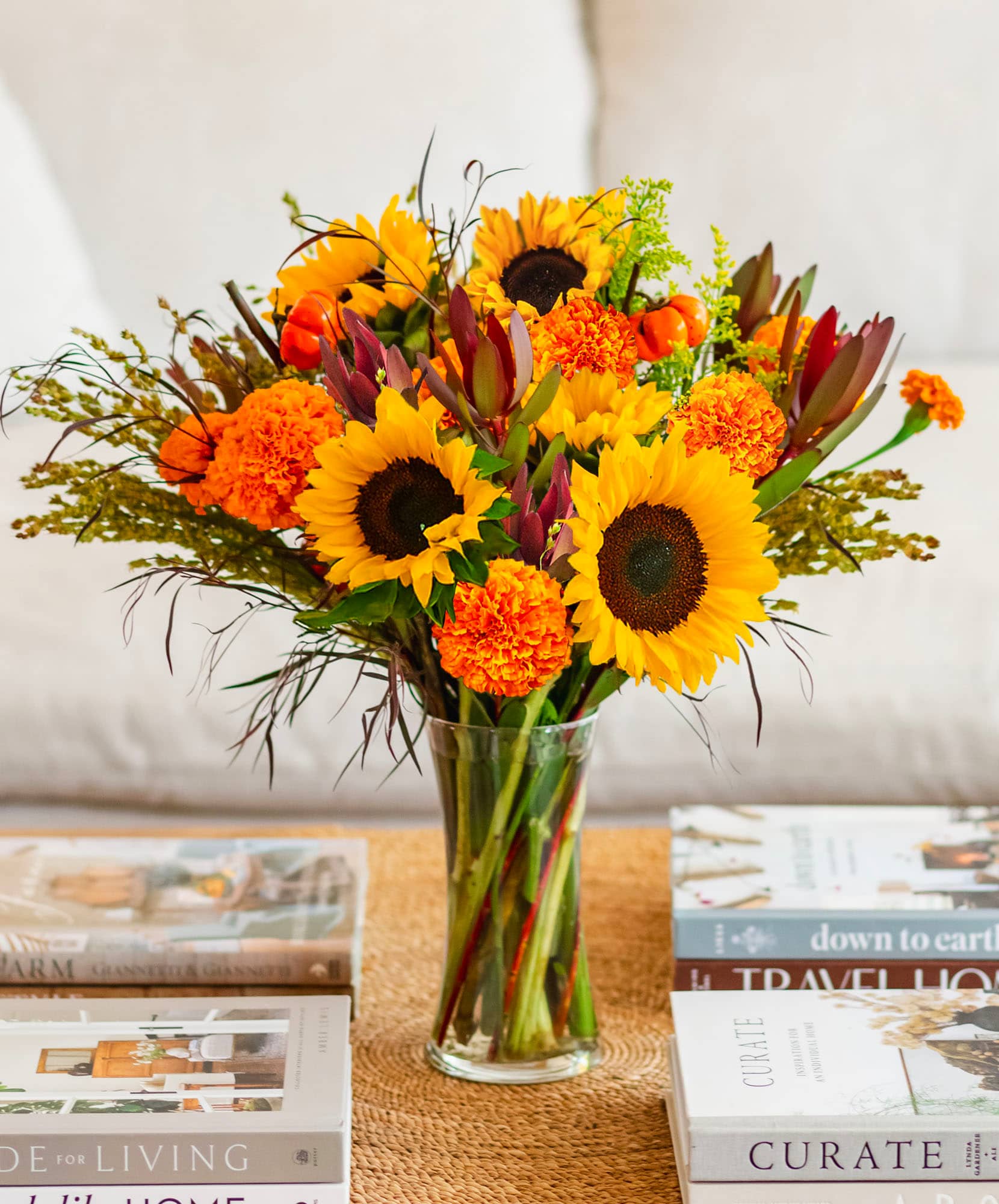 Bright and cheerful sunflower bouquet with orange marigolds in a glass vase, perfect for home decor.