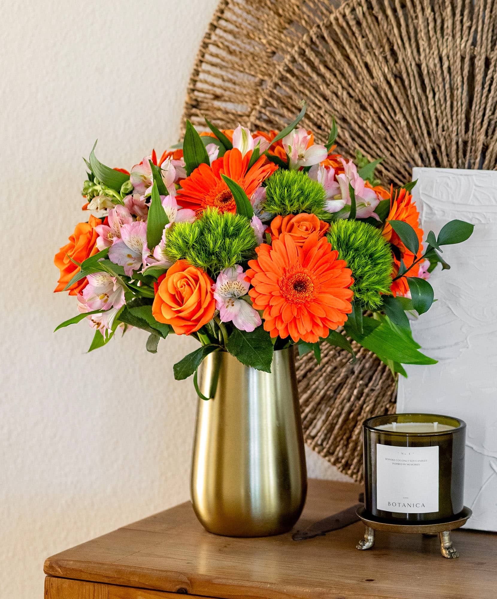 Vibrant floral arrangement featuring orange roses, gerbera daisies, and lush greenery.