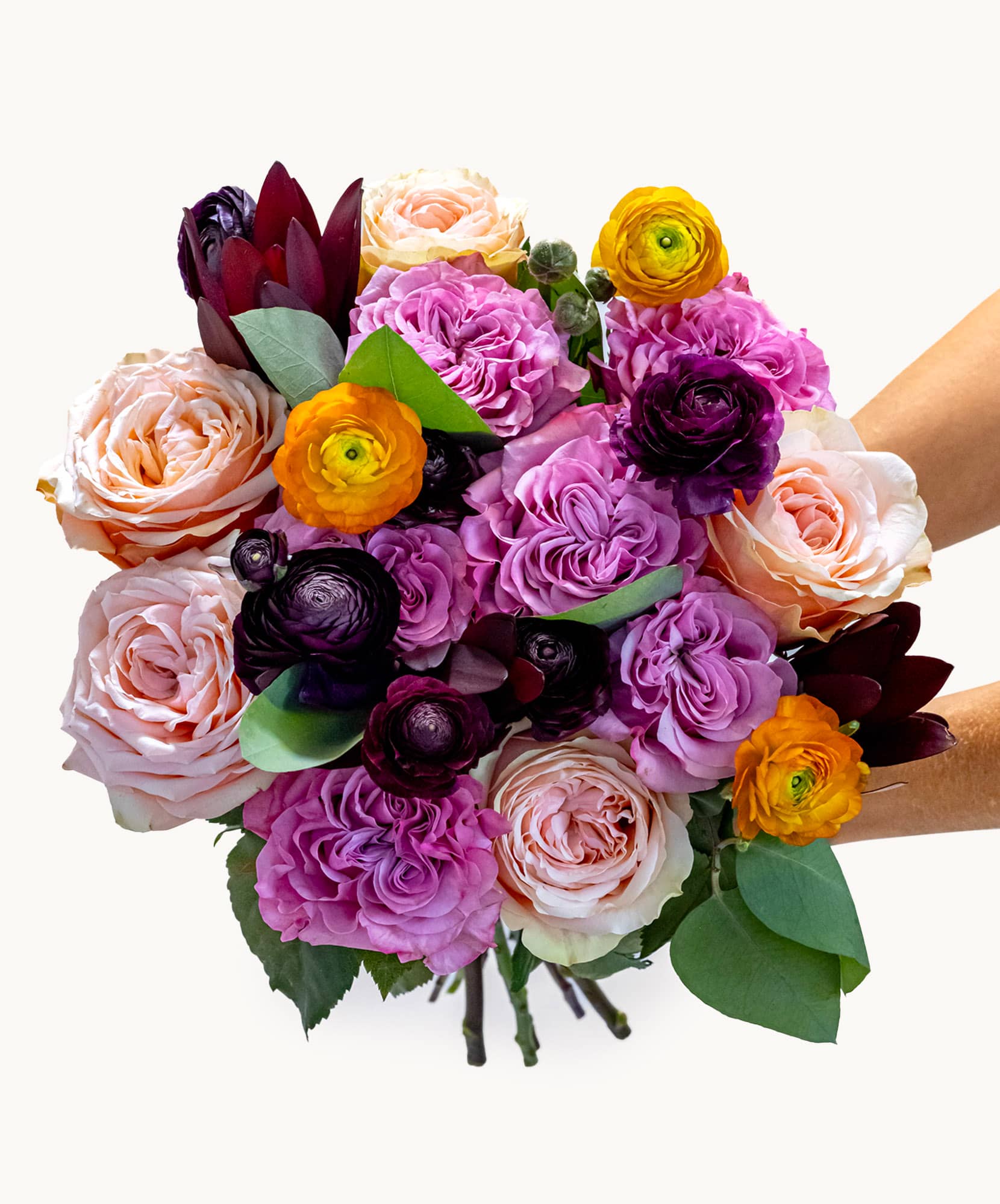 Vibrant bouquet featuring roses, ranunculus, and lush greenery in a charming arrangement.