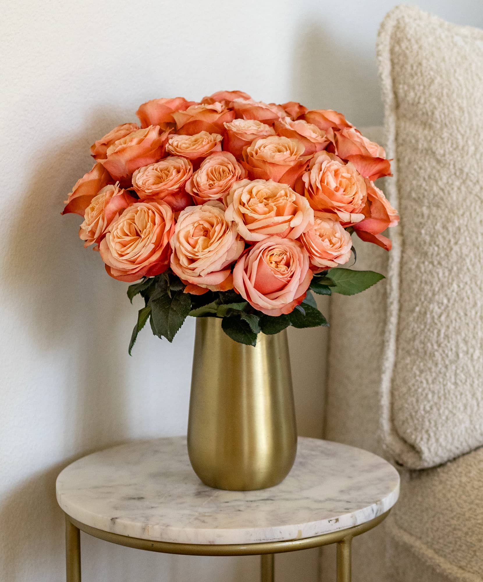 A stunning arrangement of coral roses in a chic brass vase, enhancing any decor.